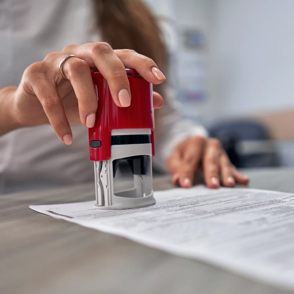 Image of a woman's hand holding a red stamp for a notary public.