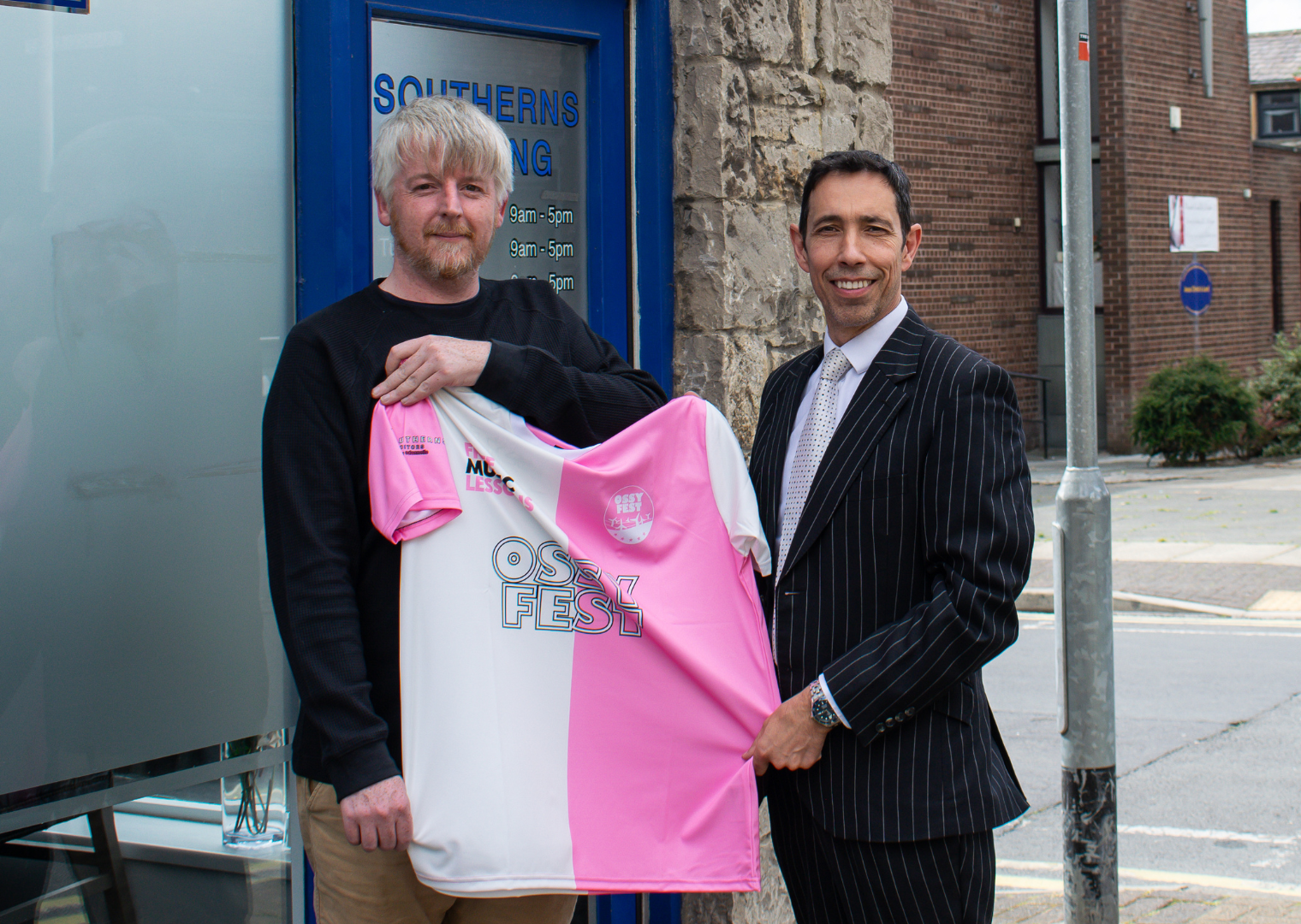 Neil Cronin, Managing Director of Southerns Solicitors and Joe Bamford the Founder of Free Music Lessons Charity holding the Limited Edition Football Shirt outside of the Southerns Solicitors Burnley office.